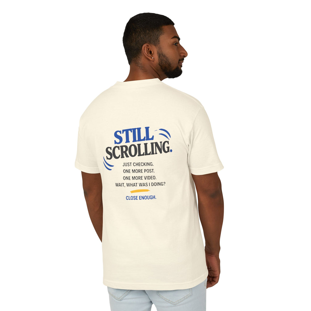 Male model wearing the Close Enough One Quick Look Tee in Faded Cream, back view with Still Scrolling graphic