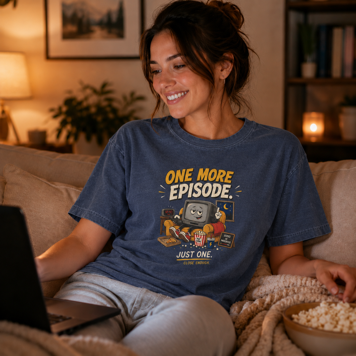 Woman wearing the ONE MORE EPISODE tee in a cozy living room
